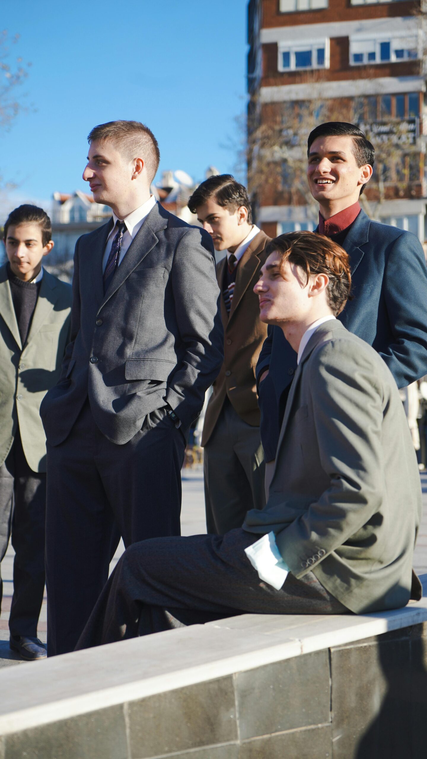 Group of young men wearing smart casual outfits including blazers and trousers in an urban setting – perfect for modern men’s style in 2025.