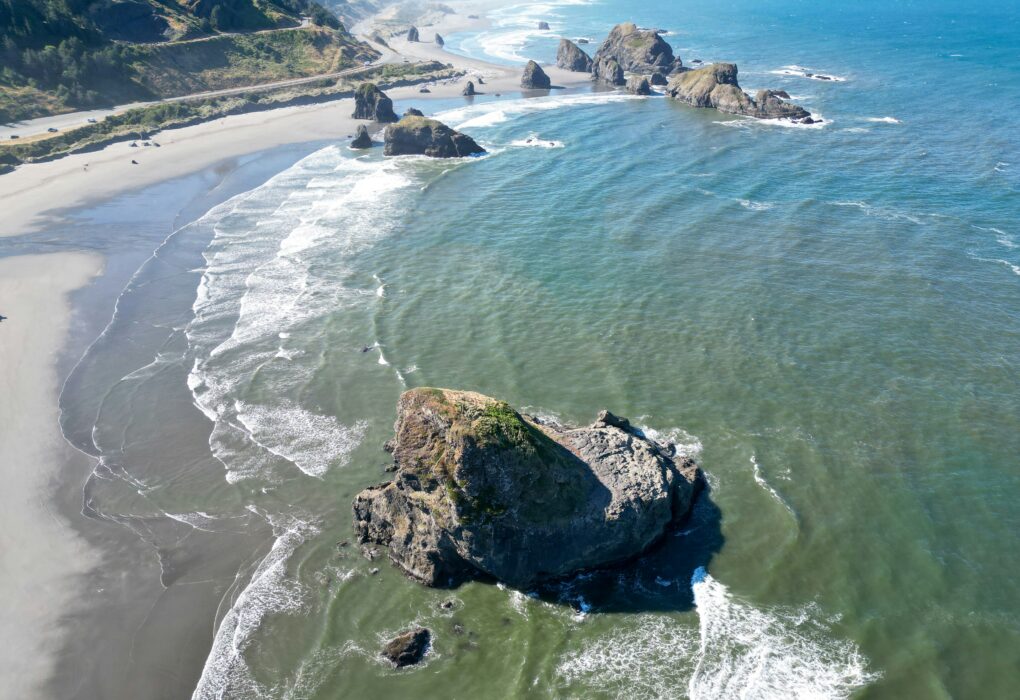 Scenic view of the Oregon Coast Road Trip 101 with cliffs, ocean waves, and sunset—perfect for a road trip adventure.